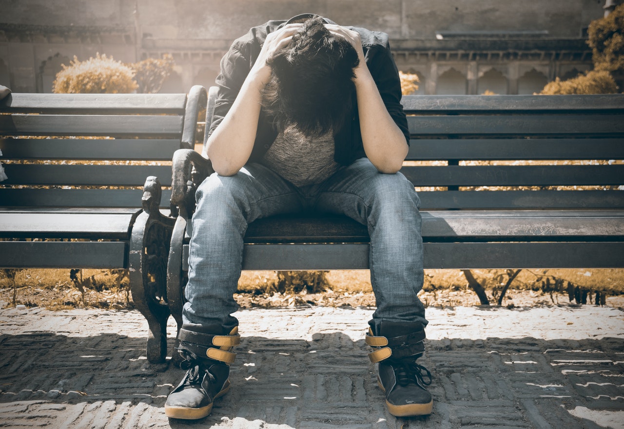 Burned out teenager with head down on bench after work